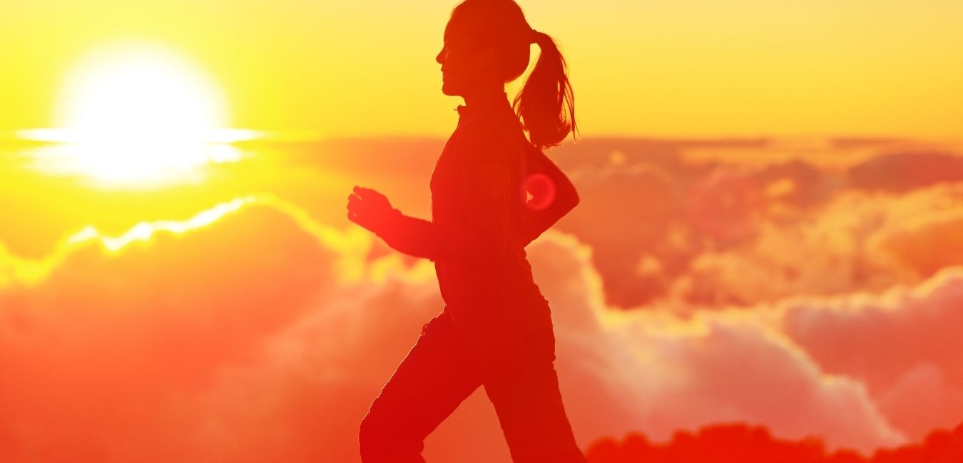 Hand weight exercises. Silhouette of a woman walking with sun and clouds in the background.