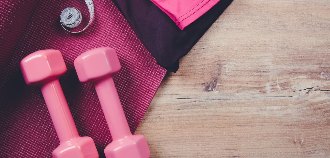 Avoiding the Big Bad 3 of Fitness Accountability. Pink hand weights on a pink yoga mat on a wood floor.