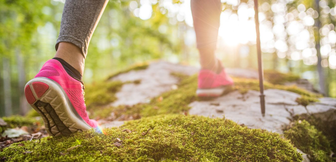 Part 1 How to Get on Track with Your Fitness - for Life! Woman's feet with hot pink sneakers hiking over a moss covered forest floor.